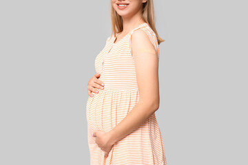 Beautiful young pregnant woman with applied medical patch on grey background