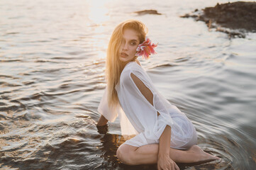 portrait of Beautiful blonde woman in water in river on sunset in golden sun beams. scoop up water in palms simple natural fairytale photography	