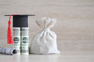 Graduation hat on banknotes and money bag on wooden background, Saving money for education concept