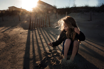 Profile beautiful young girl digging in sand sunset