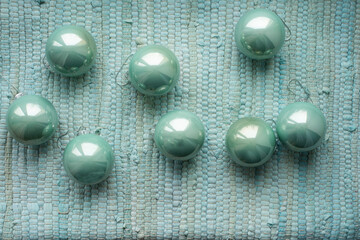 Christmas tree decorations balls mint color on a fabric woven background.