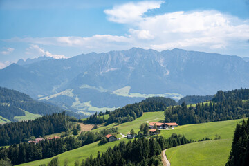 Obraz premium Panoramic view of the Zahmer Kaiser mountains in Tyrol, Austria. Forest, meadows and farms in the foreground. Blue sky with clouds