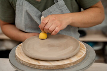 Using wooden handle sponge to smooth the surface of a clay product in a pottery workshop. Working with a sponge on a stick to shape pottery and absorb excess water from clay.