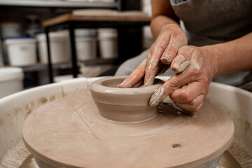 Creating a ceramic bowl by yourself in a pottery class. Wheel throwing. Learning how to model clay into different shapes with pottery wheel.