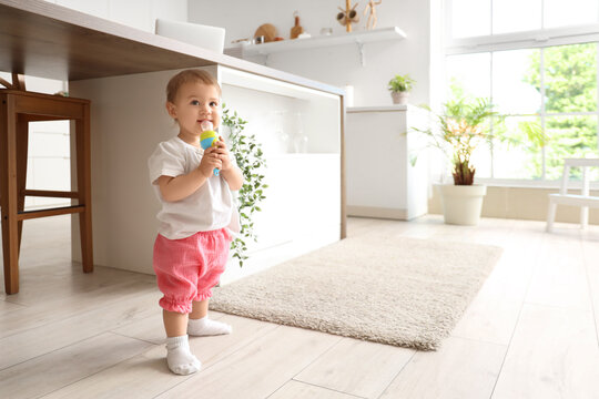Cute little baby with nibbler in kitchen