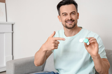 Young man with contact lenses sitting on sofa at home