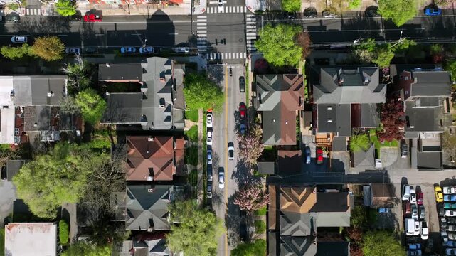 Aerial top down of junction in small american town with housing area. Driving Vehicle on road. Roof of homes during sunny day. Forward drone flight over classical rooftops.