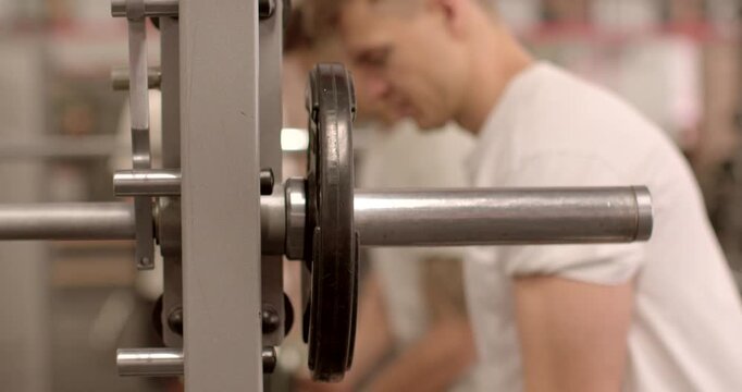 Remove the weight from the bar with your hands. Man preparation for a workout session, enthusiast is enhancing gym equipment with added weights