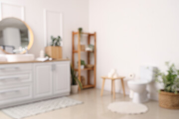 Modern toilet bowl, counter with sink, mirror and shelving unit in restroom. Blurred view