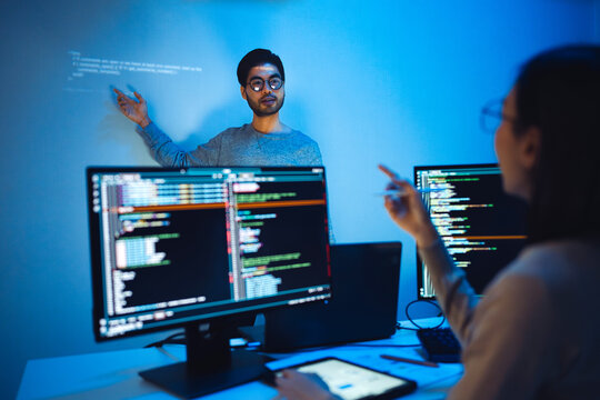 trainee developer hand up to ask speaker about software coding project presentation at night in office