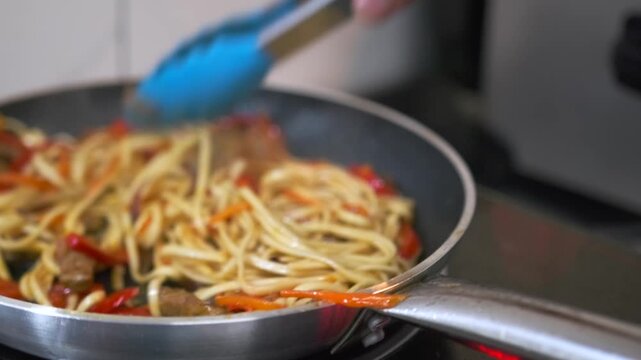 Stir fry noodles white soba with beef and vegetable in frying pan, close up, asian style food.