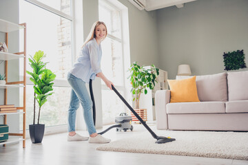 Photo of positive good mood girl dressed blue shirt vacuum cleaning carpet indoors house apartment room