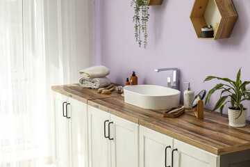 Shelf, chest of drawers with sink and bath supplies in interior of bathroom