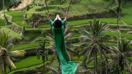 A Girl in Green Dress swinging on the rice fields of Bali