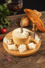 Woman gracefully slices cheese using a traditional girolle on a rustic wooden table, creating delicate cheese rosettes