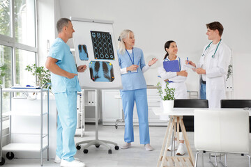 Obraz premium Group of doctors studying x-ray images on flipchart in clinic