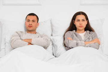 Offended young couple lying after quarrel in bedroom