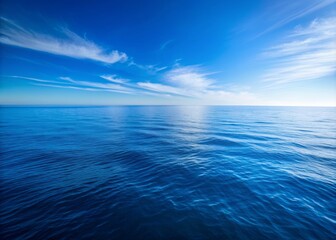 Fototapeta premium Serenene vast blue ocean stretches to horizon beneath a bright cloudless blue sky with calm waves and abundant whitespace for text overlay or design.