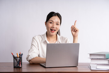 Young female businessman sitting at desk on white background