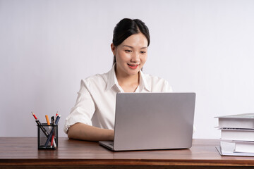 Young female businessman sitting at desk on white background