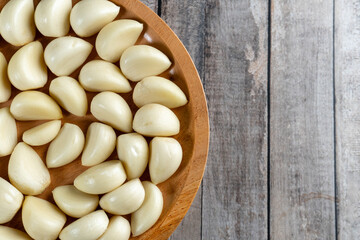 top view half of a wooden plate of garlic on wooden table