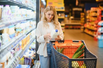 Young woman looking at product at grocery store. Costumer buying food at the market
