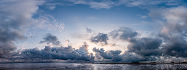 Panoramaaufnahme des dramatischen Himmels bei Sturm mit Wolkenfetzen über dem Watt bei beginnender Flut auf der Nordseeinsel Föhr