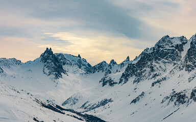 Snow-covered mountain valley with rocky peaks at sunset
