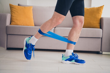 Photo of strong man doing physical exercises with rubber expander indoors house home gym