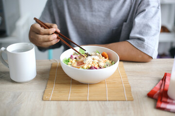 Man Eating Salad With Chopsticks At Table