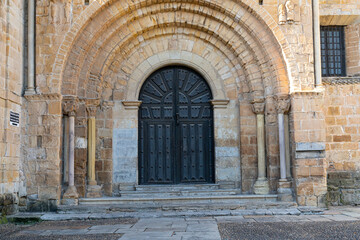 Fototapeta premium Close-up view of the architectural detail of the Collegiate Church of Santa Juliana in Santillana del Mar, Cantabria, Spain. The medieval stone structures are highlighted against a bright blue sky.