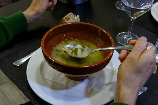 A man scoops up traditional Galician broth from a clay bowl with his spoon
Translation: "Galician broth"