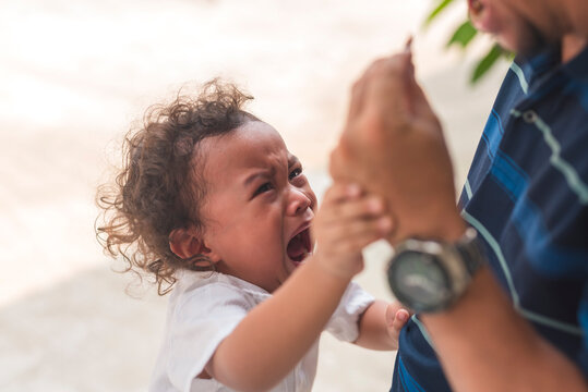 A young male toddler throws a tantrum and protests after his dirty toy is confiscated by his dad.