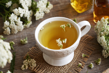 A white cup of yarrow tea with fresh plant