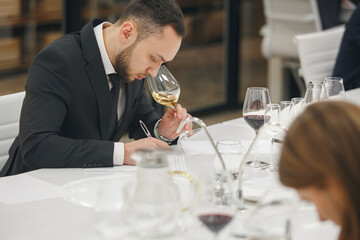 Young man sommelier tasting white wine during study in wine school. Alcoholic beverages degustation. Professional occupation.