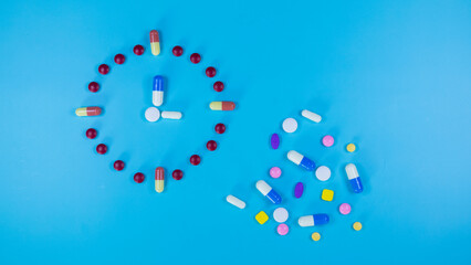 Multi-colored medications laid out in the form of labels clock and scattered on a blue background. Medicines used in medical treatment. Colorful pills and capsule. Healthcare and medical concept.