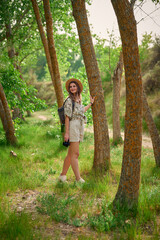 Young woman enjoying nature while taking photographs on a lush forest path during daylight