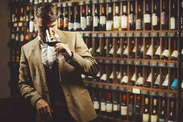 Male sommelier tasting red wine at cellar.