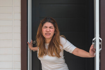 An asian woman standing right at the door annoyed at hecklers just outside her house.