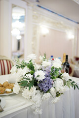 The festive table in the restaurant is decorated with a beautiful bouquet of white flowers.