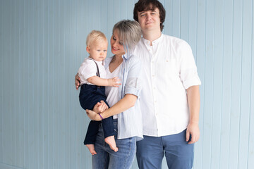 Happy family. Mother, father and their son baby boy having good time at home near blue wall