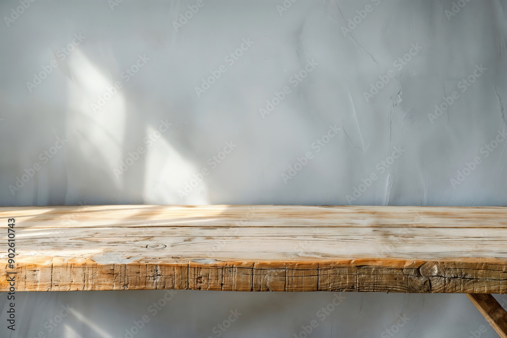 Poster empty rustic wooden tabletop against a textured wall in soft sunlight, perfect for product display