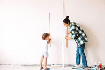 Little boy and his smiling mother choose decorations for future interior of the room. Young woman...