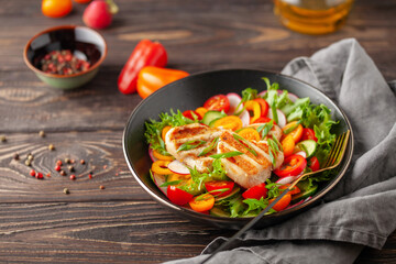 Salad with grilled chicken fillet, fresh green  leaves, cucumber, tomatoes, sweet pepper and radish. Healthy lunch salad in bowl.