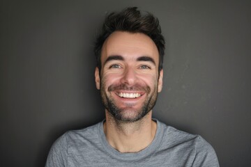Fototapeta premium A man with a beard and a smile on his face. He is wearing a gray shirt. Concept of happiness and positivity