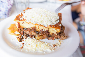 Traditional Greek moussaka served on a rustic restaurant table, showcasing rich, layered Mediterranean flavors