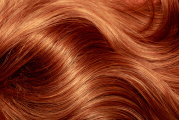 Red hair close-up as a background. Women's long orange hair. Beautifully styled wavy shiny curls....