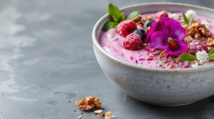 A beautifully presented purple smoothie bowl adorned with fresh raspberries, edible flowers, and nuts, perfect for a nutritious and aesthetically pleasing breakfast choice.