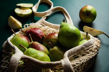 Ripe pears in a string bag on a green background