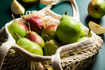 Ripe pears in a string bag on a green background